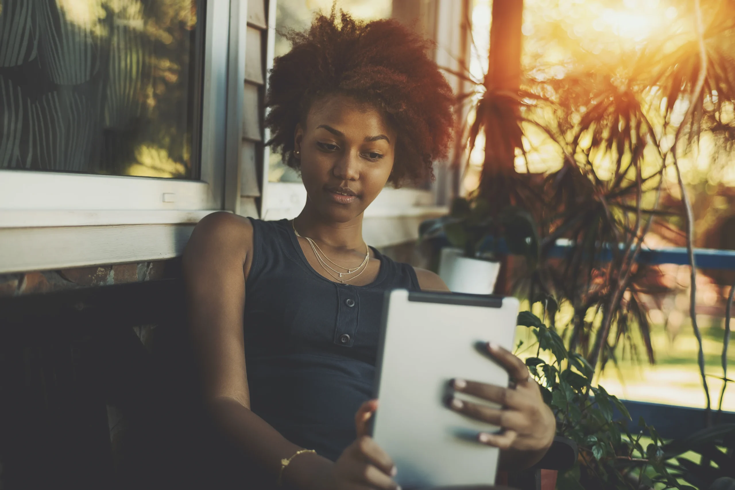 A woman using tablet sitting on warm sunlight in Brooklyn, NY | Mrs. Webb Aesthetic